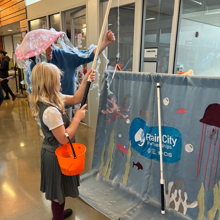 Child and volunteer play a fishing game at the event
